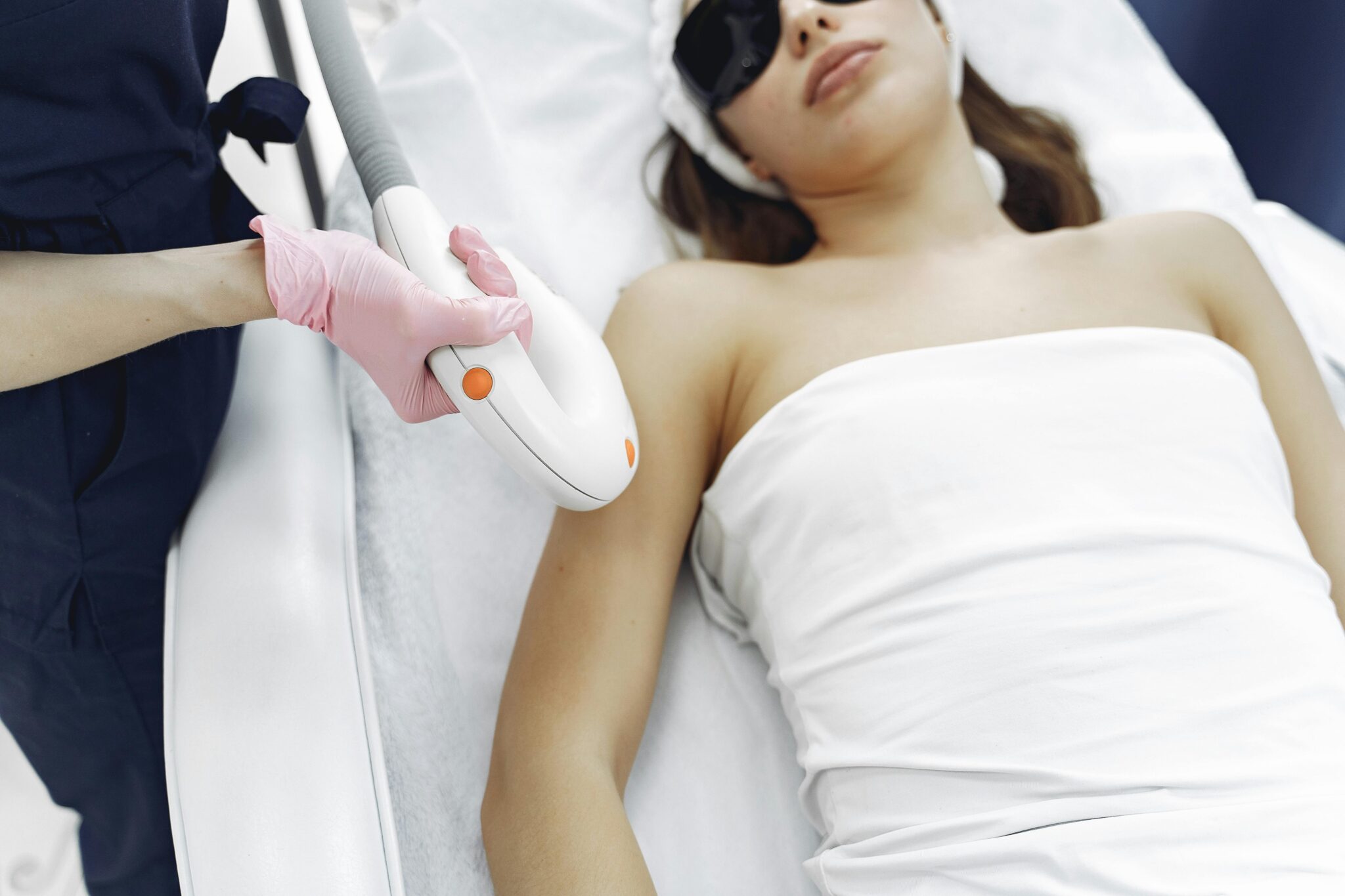 From above of unrecognizable cosmetologist in uniform and latex gloves using modern equipment for cosmetic services in contemporary salon